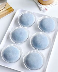 six blue desserts sitting on top of a white tray next to a cupcake tin