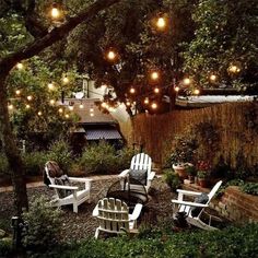 an outdoor patio with chairs and lights strung from the trees over it's back yard