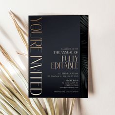 a black and gold wedding card with palm leaves on the side, in front of a white background