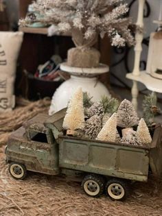 an old toy truck with trees in the back is sitting on hay next to a christmas tree