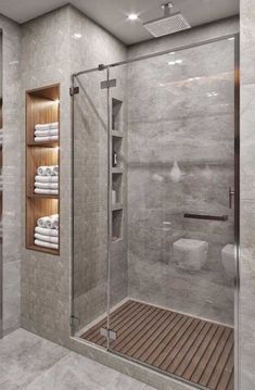 a walk in shower sitting next to a white toilet and wooden shelf filled with towels