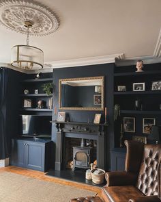 a living room with dark blue walls and leather furniture, including a brown chair in front of the fireplace