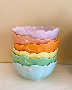 four different colored bowls stacked on top of each other in front of a beige wall