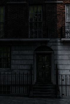 a black and white photo of an old building with a clock on the front door