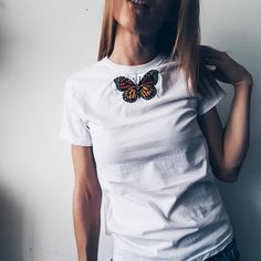 a woman wearing a white shirt with a butterfly on it