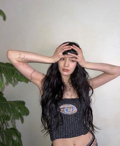 a woman with long black hair holding her hands to her head