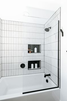 a white bath tub sitting next to a black and white tiled shower stall in a bathroom