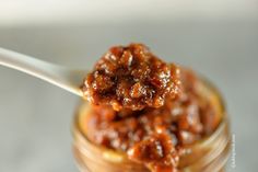 a spoon with some food in it on top of a glass jar filled with something