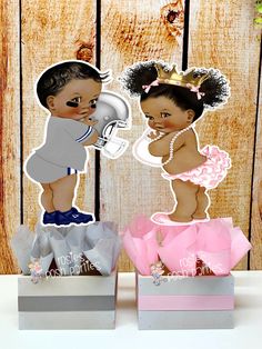 two paper cutouts of babies in diapers and bows on top of each other