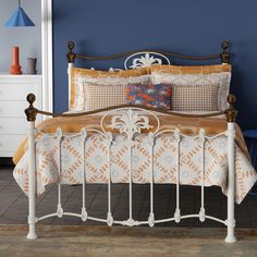 a white bed with orange and blue pillows on it's headboard in a bedroom