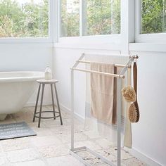 a white bath tub sitting next to a window with two towels hanging from it's bars