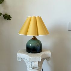 a green lamp sitting on top of a white table next to a wall mounted outlet