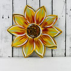 a yellow and orange flower sitting on top of a white wall