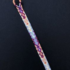 a purple and orange bracelet on a black surface with an orange hook in the middle