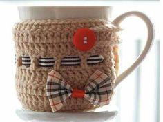 a knitted coffee cup with a bow tie on it and a button in the middle