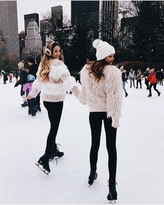 two young women walking in the snow with ear muffs on their head and one holding hands