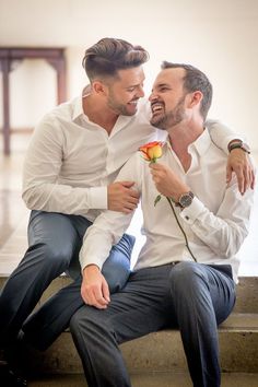 two men are sitting on the steps and one is holding a flower