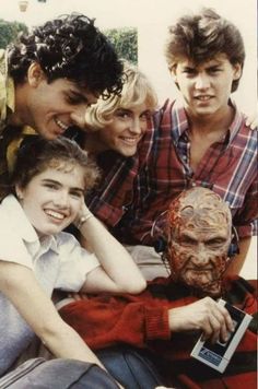 four young people posing for a photo with a creepy mask