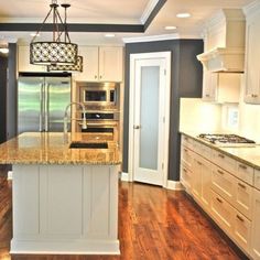 a large kitchen with white cabinets and an island in the middle of the room is lit by a chandelier