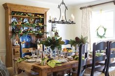 the dining room table is set with blue and white china, pine cones, greenery, and candlesticks