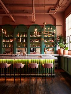 a bar with pink chairs and green cabinets