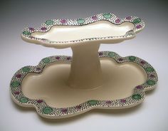 two white dishes with green and pink designs on them, one sitting on top of the other