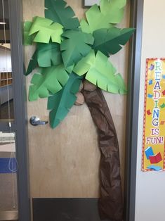 a palm tree made out of paper sitting on top of a wooden table next to a door