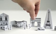 a hand is pointing at some miniature buildings