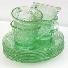 three green glass dishes sitting on top of each other with one bowl and two cups