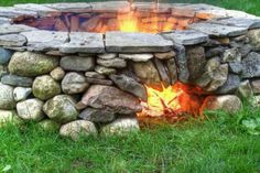 a fire pit made out of rocks in the grass