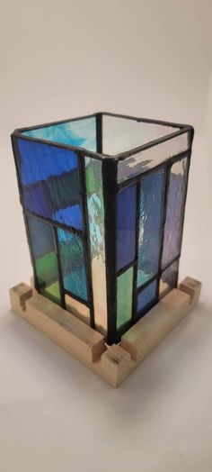 a stained glass vase sitting on top of a wooden stand