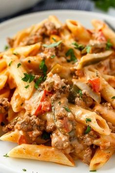 a white plate topped with pasta covered in meat and sauces on top of it