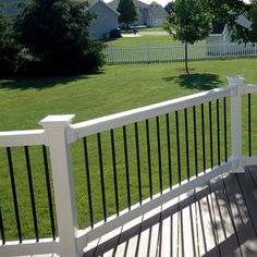 a white deck with black railings and green grass