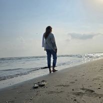 a woman standing on top of a beach next to the ocean