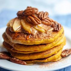 a stack of pancakes topped with pecans and maple syrup