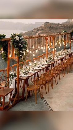 a long table set up with flowers and greenery on it for an outdoor dinner