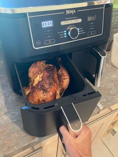 a person is holding a roasting pan with a turkey in it and the oven door open