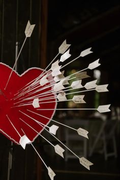 a red heart with white arrows sticking out of it's center and writing on the sides