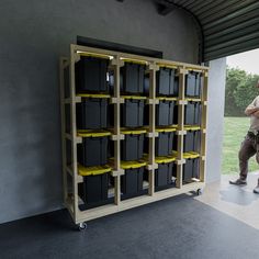 a man standing in front of a shelf filled with bins