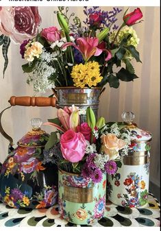 a vase filled with flowers sitting on top of a table next to two tea kettles