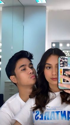 a man and woman taking a selfie in front of a mirror with their cell phones