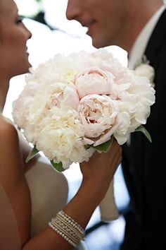 the bride and groom are kissing with their bouquets in front of each other on their wedding day