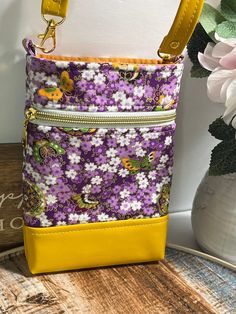 a purple and white flowered purse sitting on top of a table next to flowers