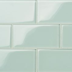 a close up view of a white tile wall with light green grouting on it