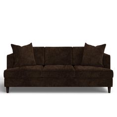 a brown couch sitting on top of a white floor next to two black pillows and a wooden frame