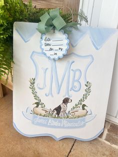 a sign with a dog on it that says j m b and has a green bow