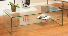 a glass coffee table sitting on top of a hard wood floor next to a potted plant