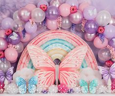 a pink and purple backdrop with balloons, butterflies, and an arch in the center