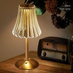 a lamp that is sitting on top of a table next to a radio and flowers