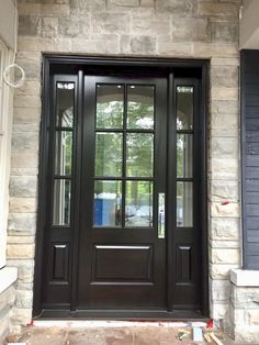 a black front door with two sidelights and glass panels on the outside of it